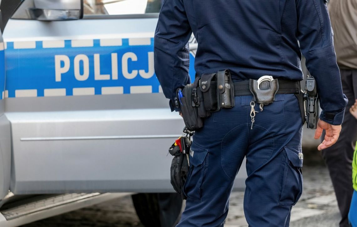 Policjant stoi przy policyjnym wozie