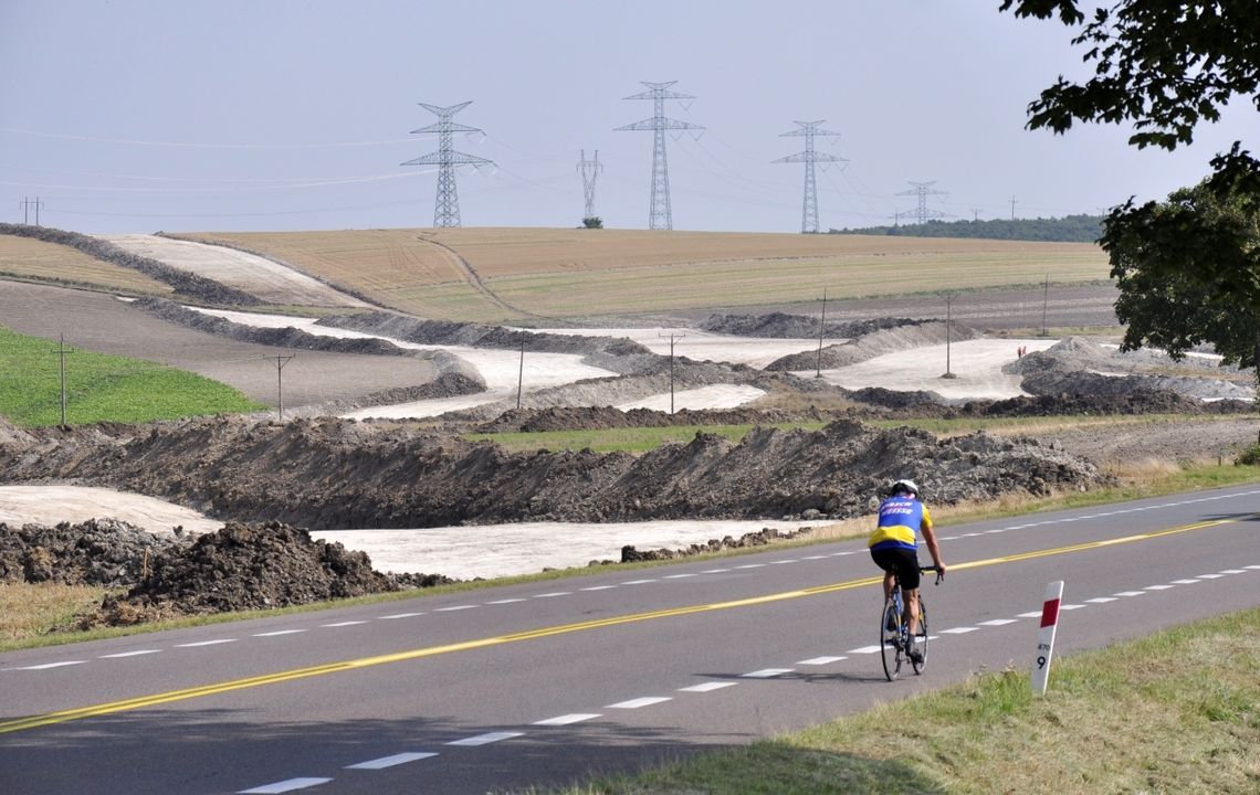 rowerzysta na drodze krajowej nr 12, a w tle budowa obwodnicy chełma